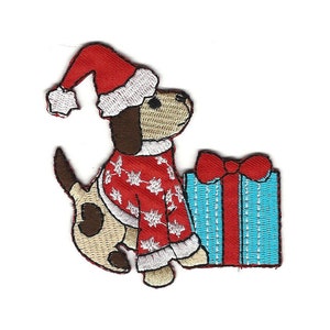 May include: Embroidered iron-on patch of a dog wearing a red and white sweater and a Santa hat, holding a blue and white gift box with a red bow.