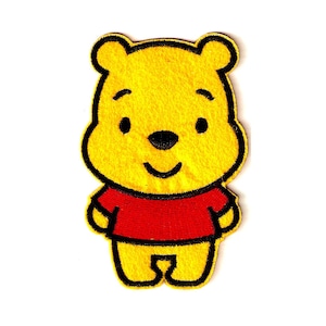May include: A yellow Winnie the Pooh patch with a black outline. The bear is wearing a red shirt and has a black nose and eyes. The patch is on a white background.