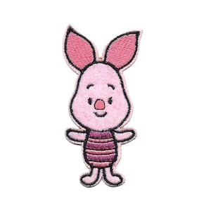 May include: Embroidered patch featuring a pink cartoon character with large ears, a small nose, and a striped torso. The character has a black outline and is standing with arms outstretched. The patch is designed for application on clothing or accessories.