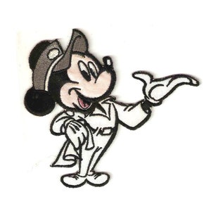 Puede incluir: Un parche bordado en blanco y negro para planchar con Mickey Mouse vistiendo un traje blanco y un sombrero marrón. Está sonriendo y saludando con la mano derecha.
