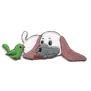 May include: Embroidered iron-on patch featuring a white dog with brown ears lying down and looking at a green bird.