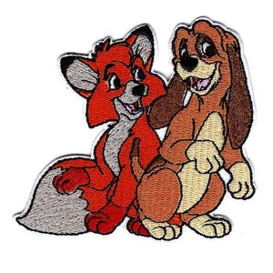 May include: Embroidered patch featuring a cartoon fox and hound. The fox is primarily orange with a white and gray tail, while the hound is brown and tan. Both characters are smiling, with the patch having a white border.