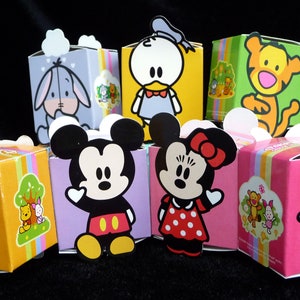 Könnte beinhalten: Satz von neun bunten Pappkartons mit verschiedenen Disney-Charakteren, darunter Mickey Mouse, Minnie Mouse, Winnie Puuh, Tigger, Eeyore und Donald Duck. Jede Schachtel hat einen anderen Charakter und ein anderes Farbschema.