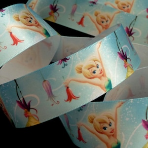 Puede incluir: Cinta de satén azul con un patrón repetido de Campanilla volando con flores. La cinta tiene aproximadamente 1 pulgada de ancho.