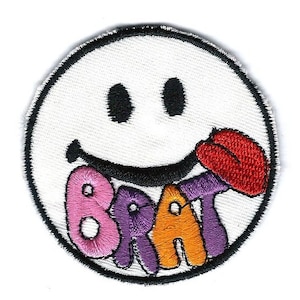 Pode incluir: Um rosto sorridente branco com contorno preto e lábios vermelhos é mostrado com a palavra "BRAT" em letras coloridas. As letras são rosa, roxo, laranja e roxo.
