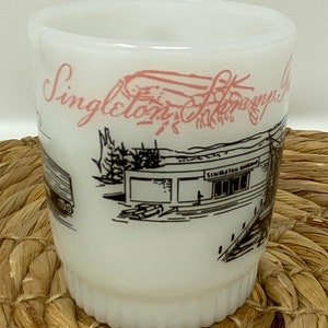 May include: White ceramic mug with a black and white illustration of a building with the text "Singleton Shrimp Co." in pink lettering.