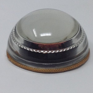 May include: A silver magnifying glass with a clear glass lens and a gold trim around the base.