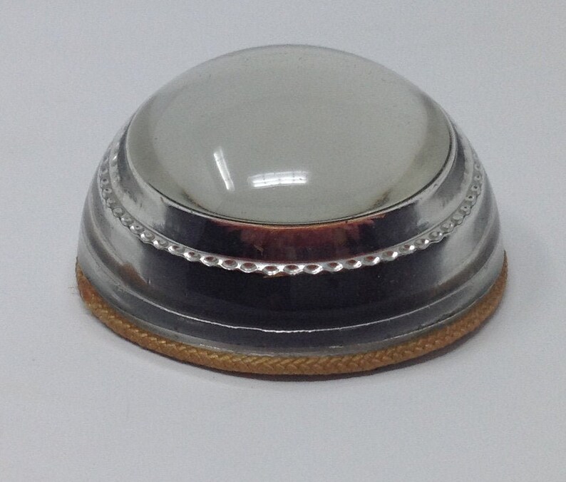 May include: A silver magnifying glass with a clear glass lens and a gold trim around the base.