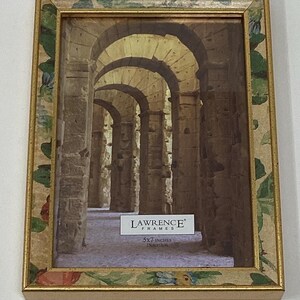 May include: A gold picture frame with a floral design and a beige mat. The frame is 5x7 inches and has a label that says "Lawrence Frames". The image inside the frame is a photograph of an arched hallway.