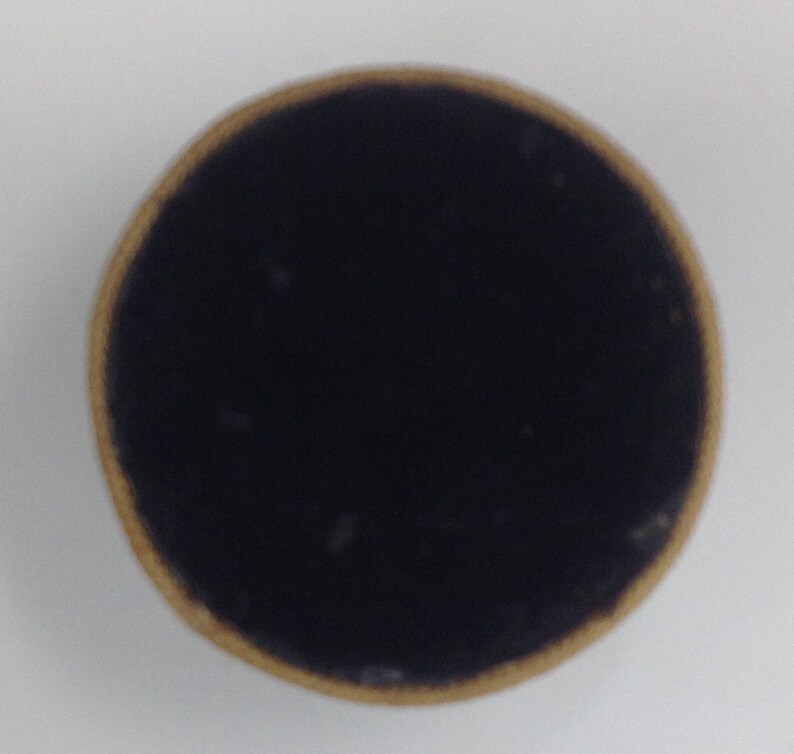 May include: A close-up of a round cardboard box lid with a black velvet lining.