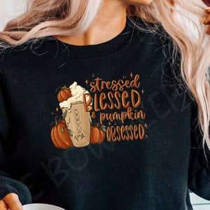 May include: A black sweatshirt with the text "stressed blessed & pumpkin obsessed" and a graphic of a pumpkin spice latte.
