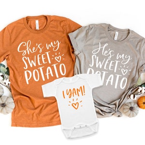 Puede incluir: Tres camisetas con tem&aacute;tica de Acci&oacute;n de Gracias. Las camisetas para adultos son naranja y gris con el texto "She's my sweet potato" y "He's my sweet potato". La camiseta para beb&eacute; es blanca con el texto "I yam!" y un coraz&oacute;n.