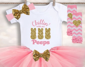 May include: A pink tutu, white bodysuit with the text "Chillin' with my Peeps", a pink and white leg warmer with a gold heart, and a pink headband with a gold bow.