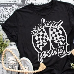 May include: Black t-shirt with white text that reads "Weekend Forecast" and a graphic of two chequered flags.