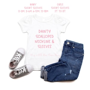May include: White short-sleeved t-shirt with pink text that reads "DAINTY SCALLOPED NECKLINE & SLEEVES" and "My Little Bow Peeps Shop".