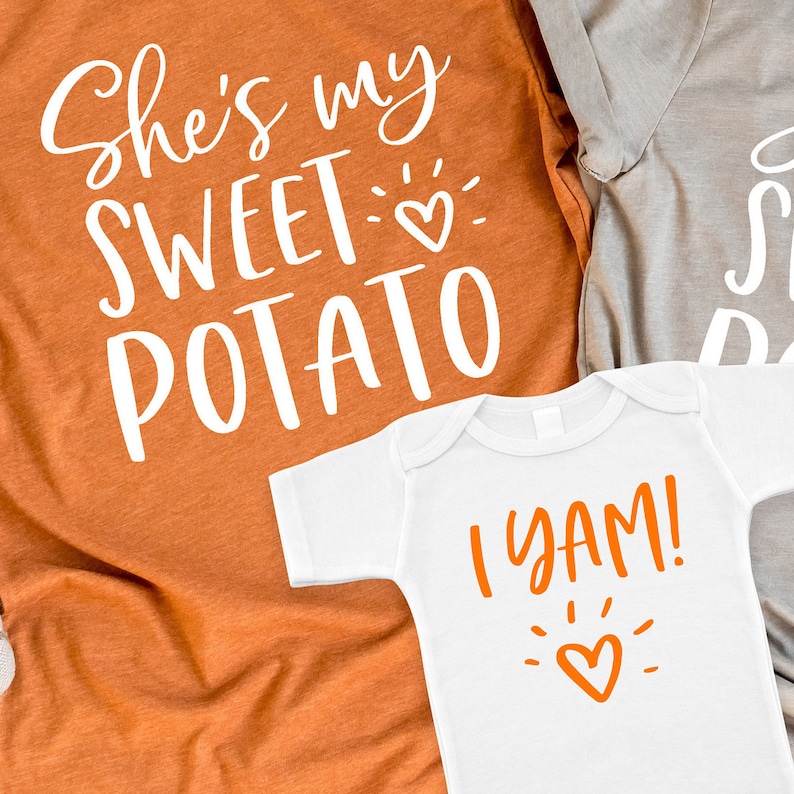 Puede incluir: Dos camisetas con tem&aacute;tica de Acci&oacute;n de Gracias. La camiseta m&aacute;s grande es naranja y dice "She's my sweet potato" con un peque&ntilde;o coraz&oacute;n. La camiseta m&aacute;s peque&ntilde;a es blanca y dice "I yam!" con un coraz&oacute;n.