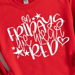 K&ouml;nnte beinhalten: Roter Pullover mit wei&szlig;em Text, der "On Fridays we wear red" mit Sternen und einem Herzen lautet.