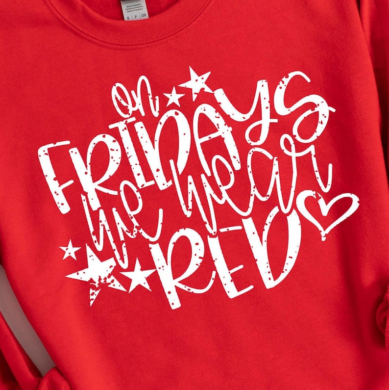 K&ouml;nnte beinhalten: Roter Pullover mit wei&szlig;em Text, der "On Fridays we wear red" mit Sternen und einem Herzen lautet.