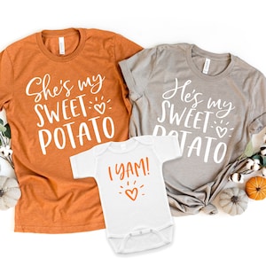 Puede incluir: Tres camisetas blancas con texto naranja. La camiseta m&aacute;s grande dice "She's my sweet potato" con un peque&ntilde;o coraz&oacute;n. La camiseta mediana dice "He's my sweet potato" con un peque&ntilde;o coraz&oacute;n. La camiseta m&aacute;s peque&ntilde;a dice "I yam!" con un peque&ntilde;o coraz&oacute;n.
