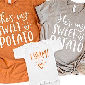 Puede incluir: Tres camisetas con tem&aacute;tica de Acci&oacute;n de Gracias. La camiseta m&aacute;s grande es naranja y dice "She's my sweet potato" con un peque&ntilde;o coraz&oacute;n. La camiseta mediana es gris y dice "He's my sweet potato" con un peque&ntilde;o coraz&oacute;n. La camiseta m&aacute;s peque&ntilde;a es blanca y dice "I yam!" con un peque&ntilde;o coraz&oacute;n naranja.