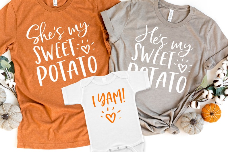 Puede incluir: Tres camisetas con tem&aacute;tica de Acci&oacute;n de Gracias. La camiseta m&aacute;s grande es naranja y dice "She's my sweet potato" con un peque&ntilde;o coraz&oacute;n. La camiseta mediana es gris y dice "He's my sweet potato" con un peque&ntilde;o coraz&oacute;n. La camiseta m&aacute;s peque&ntilde;a es blanca y dice "I yam!" con un peque&ntilde;o coraz&oacute;n naranja.