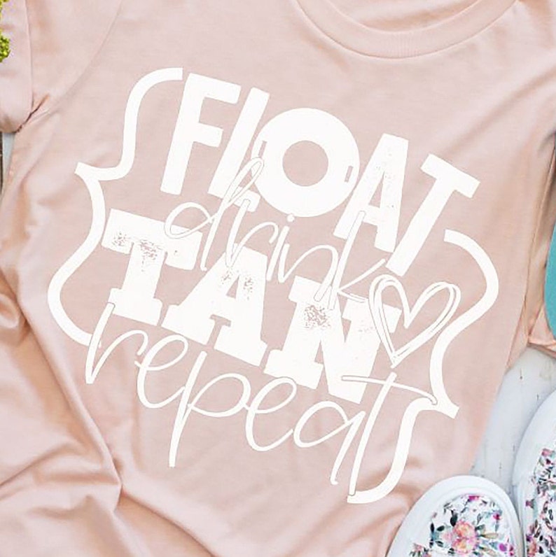 以下が含まれることがあります： 白い文字で「FLOAT drink TAN repeat」と書かれたピンクのTシャツ。テキストはハートと円形でスタイリッシュにデザインされています。