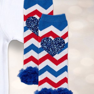 May include: A pair of red, white, and blue chevron leg warmers with blue glitter hearts. The leg warmers have a blue ruffle at the bottom.