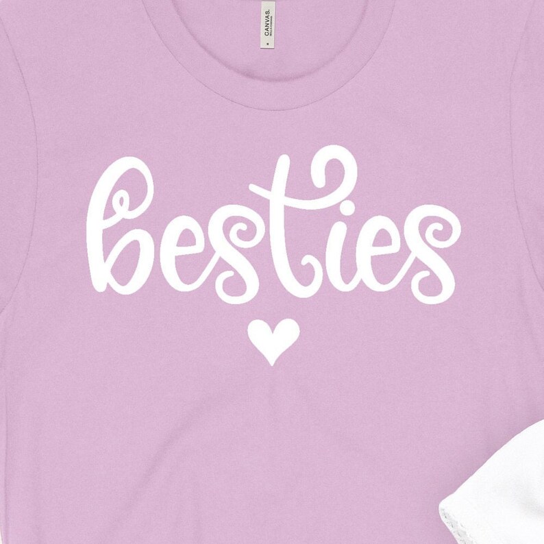 K&ouml;nnte beinhalten: Ein lavendelfarbenes T-Shirt mit dem Wort "besties" in wei&szlig;er Kursivschrift und einem wei&szlig;en Herzen darunter.