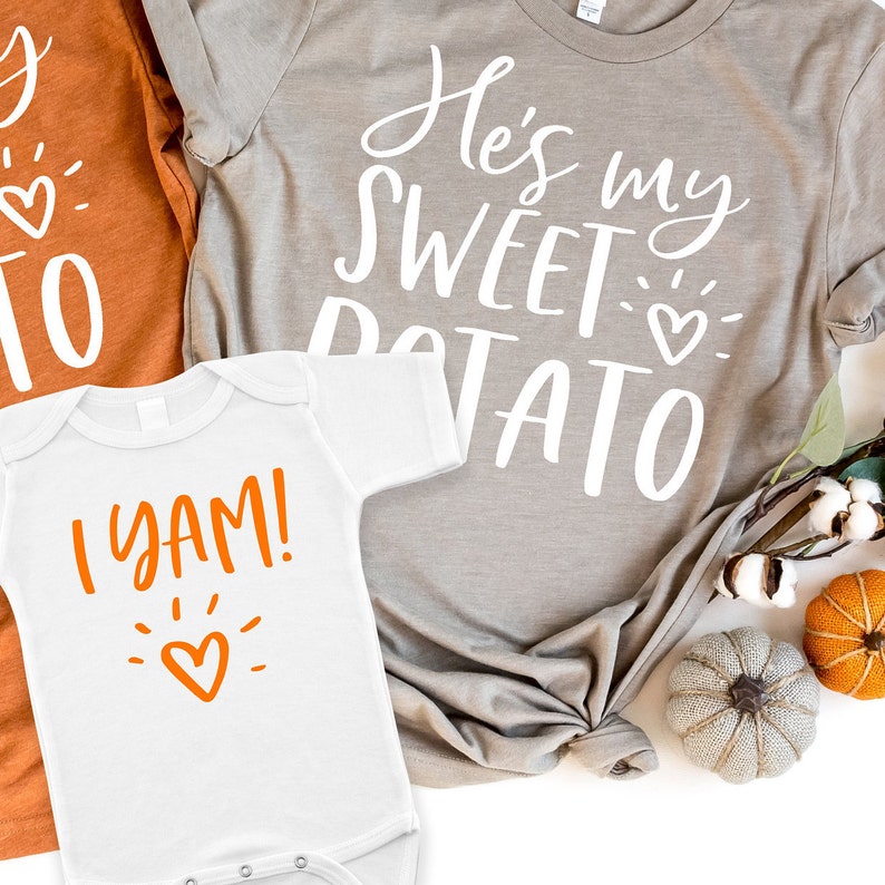 Puede incluir: Dos camisetas con tem&aacute;tica de Acci&oacute;n de Gracias. La camiseta m&aacute;s grande es gris con texto blanco que dice "He's my sweet potato" con un peque&ntilde;o coraz&oacute;n naranja. La camiseta m&aacute;s peque&ntilde;a es blanca con texto naranja que dice "I yam!" con un peque&ntilde;o coraz&oacute;n naranja.