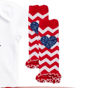 May include: Red and white chevron leg warmers with a blue glitter heart on each. The leg warmers have a ruffled edge.