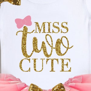 May include: White onesie with a pink bow and gold glitter lettering that says "Miss Two Cute".