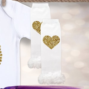 May include: White long-sleeved shirt with gold glitter hearts. White leg warmers with gold glitter hearts and white ruffles at the bottom.