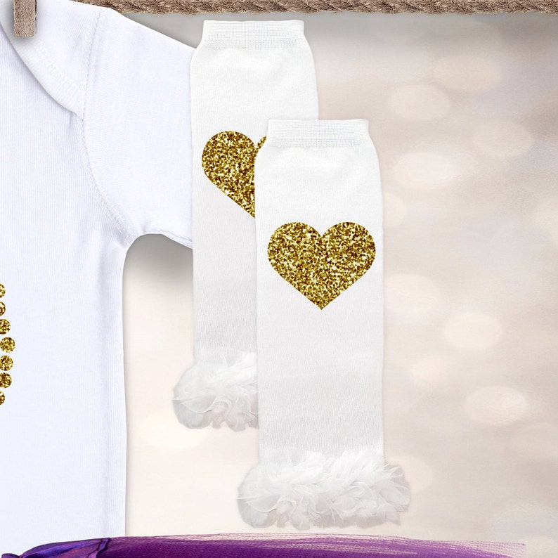 May include: White long-sleeved shirt with gold glitter hearts. White leg warmers with gold glitter hearts and white ruffles at the bottom.