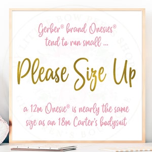 May include: A white sign with pink text that reads "Gerber brand Onesies tend to run small... Please Size Up a 12m Onesie is nearly the same size as an 18m Carter's bodysuit"