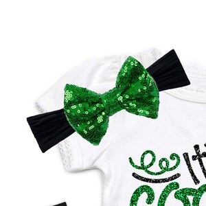 May include: A white shirt with a green sequin bow headband. The shirt has black sequin lettering that says "Let's Get Lit".