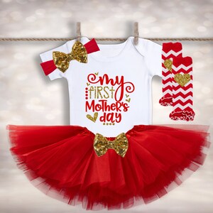 Puede incluir: Conjunto de beb&eacute; con un body blanco con texto rojo y dorado "My First Mother's Day". El conjunto incluye un tut&uacute; rojo, una diadema y calcetines. Decorado con lazos dorados con lentejuelas y calcetines con estampado de chevron rojo y blanco.