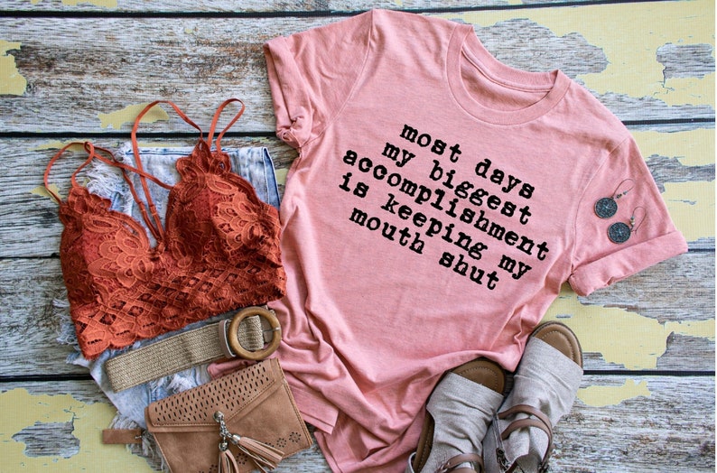 May include: A pink t-shirt with the text "Most days my biggest accomplishment is keeping my mouth shut".