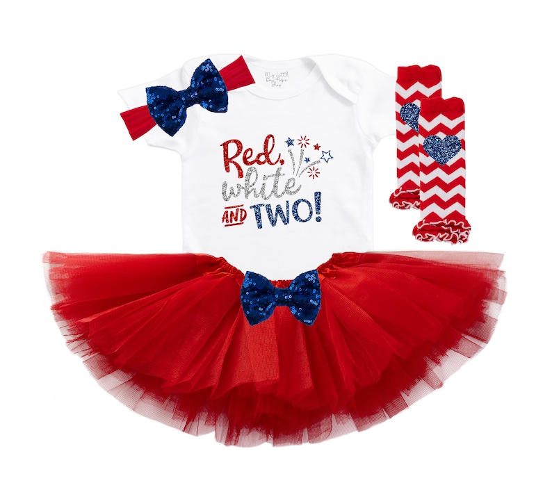 May include: Red, white and two! A white bodysuit with red, white, and blue glitter text, a red tulle tutu, a red and white striped leg warmer with a blue heart, and a red headband with a blue bow.