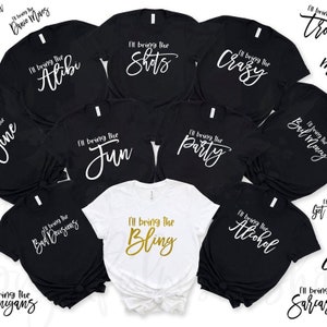 May include: Ten black t-shirts with white text and one white t-shirt with gold text. The shirts all have the phrase "I'll bring the" followed by a different word. The words are "Alibi", "Shots", "Crazy", "Fun", "Party", "Bad Decisions", "Bling", "Alcohol", "Soul Money", "Get", and "Sarcasm".