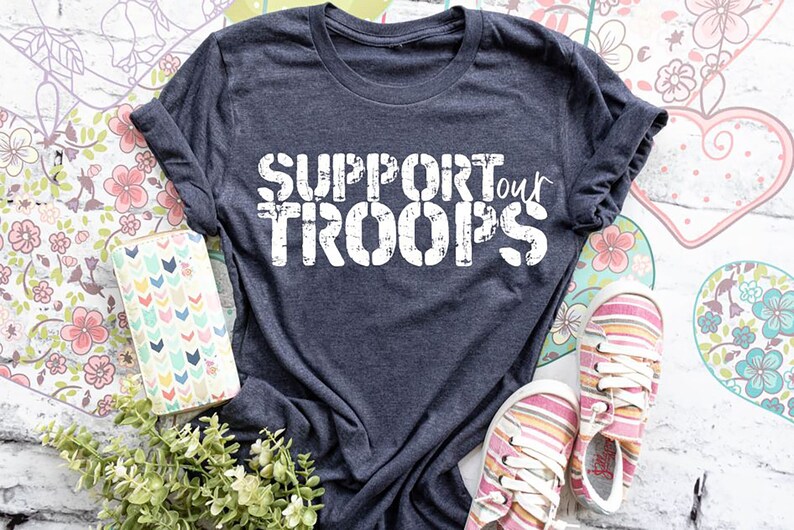 May include: A dark gray t-shirt with the text "SUPPORT our TROOPS" in white distressed lettering.