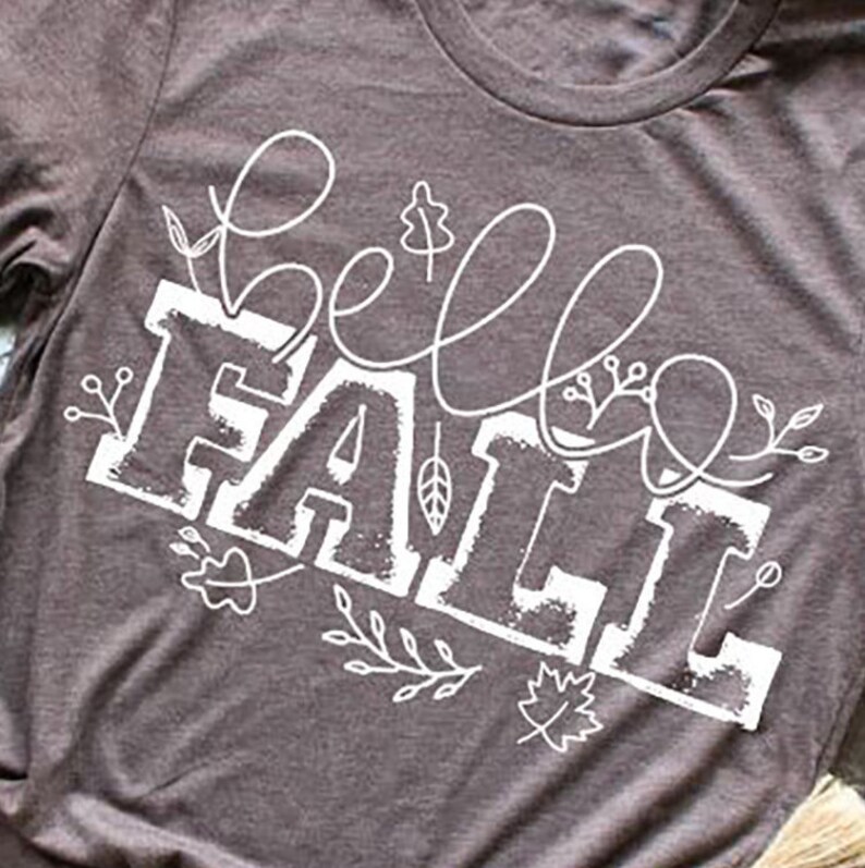 May include: A brown t-shirt with a white graphic that says "hello fall" with stylized leaves and vines.