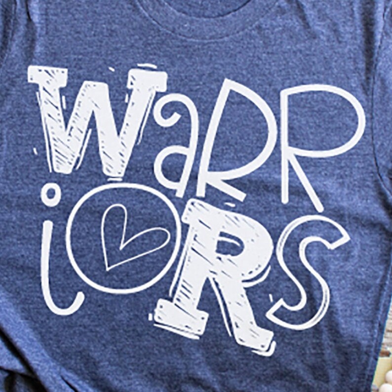 K&ouml;nnte beinhalten: Ein blaues T-Shirt mit dem Schriftzug "WARRIORS" in Wei&szlig;, wobei ein Herz in der Mitte des Wortes "WARRIORS" platziert ist.