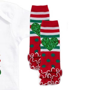May include: Red and green striped leg warmers with a green glitter heart on each. The leg warmers have a white ruffle at the bottom.