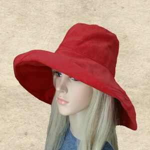 Puede incluir: Un sombrero de sol rojo de ala ancha con un dise&ntilde;o sencillo. El sombrero est&aacute; hecho de una tela suave y ligera y tiene un ala ancha que proporciona una amplia sombra.