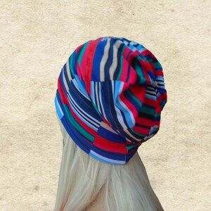 May include: A colorful striped beanie hat with red, blue, green, white, and black stripes. The hat is made of a soft, stretchy fabric and is perfect for keeping your head warm in the winter.