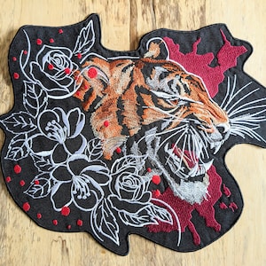 May include: Black embroidered patch featuring a snarling tiger head with orange and black stripes. The background is red with white floral designs.