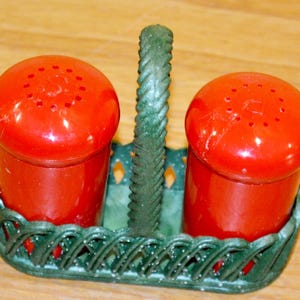 Peut inclure: Un ensemble sel et poivre rouge vintage. Les salières et poivrières ont un design classique avec une forme ronde et des trous sur le dessus. Elles sont placées dans un support vert en forme de panier avec une poignée. L'ensemble est en plastique.