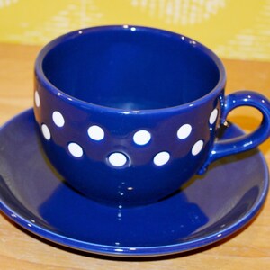 May include: A blue and white polka dot teacup and saucer set. The cup and saucer are both a deep blue color with white polka dots.