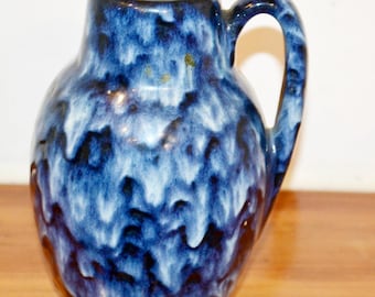 May include: A blue and white ceramic vase with a handle. The vase has a mottled glaze with a dark blue base.
