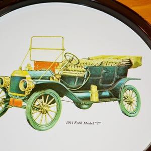 Könnte beinhalten: Rundes Serviertablett mit einer Vintage-Illustration eines Ford Model "T" von 1911. Das Auto ist in Grün, Gelb und Schwarz dargestellt, vor einem weißen Hintergrund mit einem dunkelbraunen Rand. Der Text "1911 Ford Model "T"" ist darunter gedruckt.